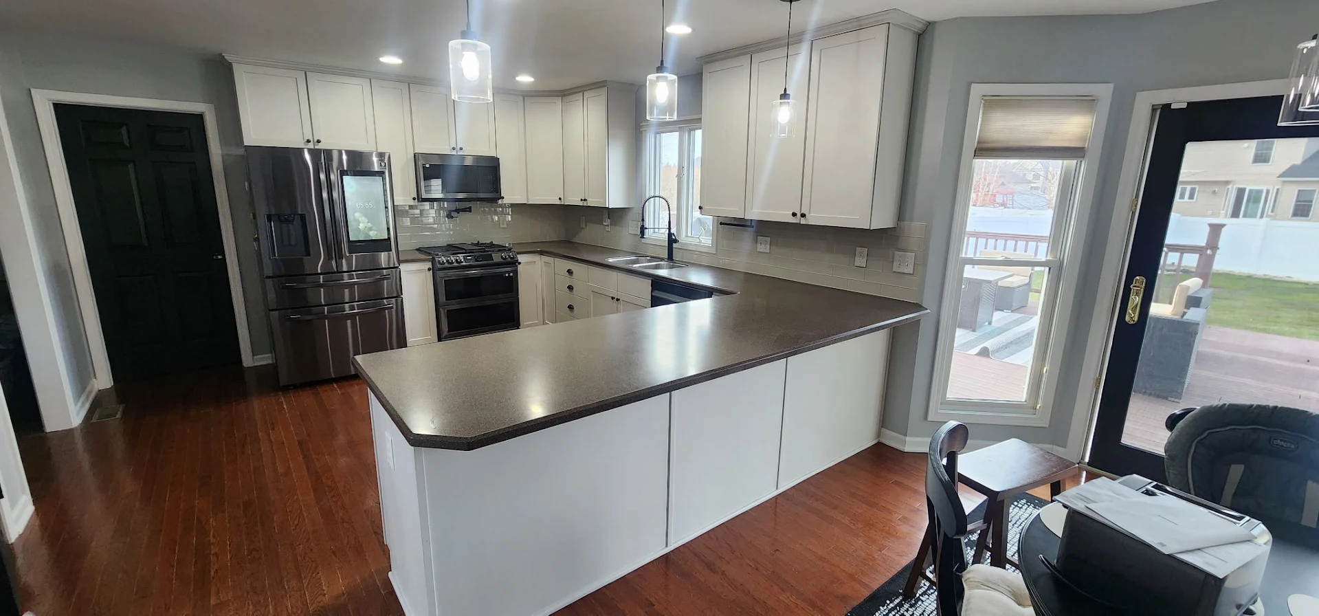 Full kitchen remodel with island, white shaker cabinets, and dark quartz countertops