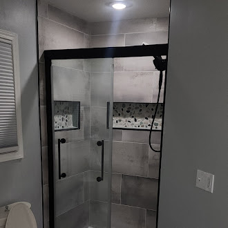 Custom frameless glass shower enclosure with large-format tile and black matte fixtures